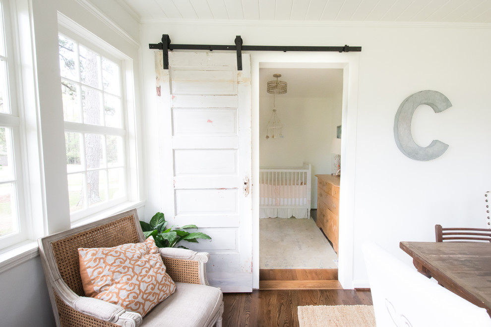 Photo of a small rustic nursery for girls in Atlanta with white walls and dark hardwood flooring.