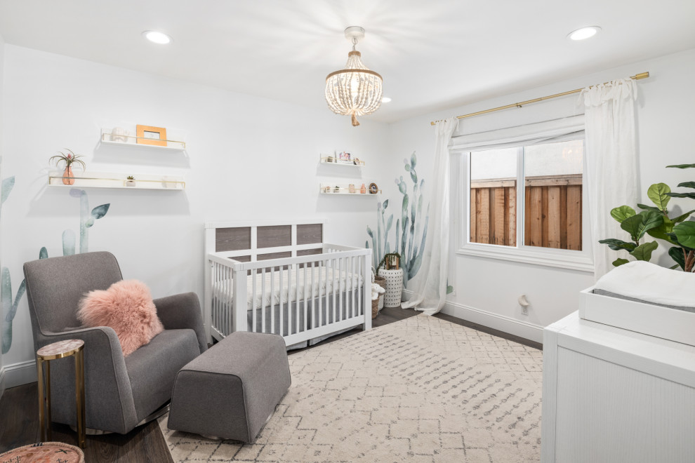 Imagen de habitación de bebé niña clásica renovada grande con paredes blancas, suelo de madera en tonos medios y suelo marrón