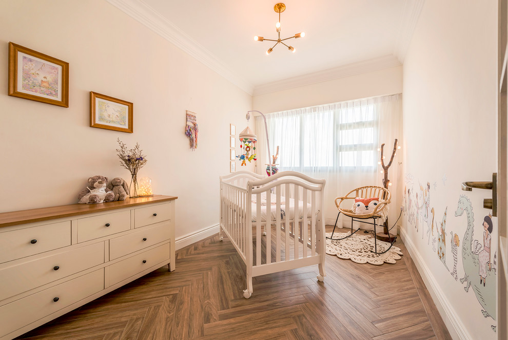 Ejemplo de habitación de bebé clásica con paredes rosas, suelo de madera en tonos medios y suelo marrón