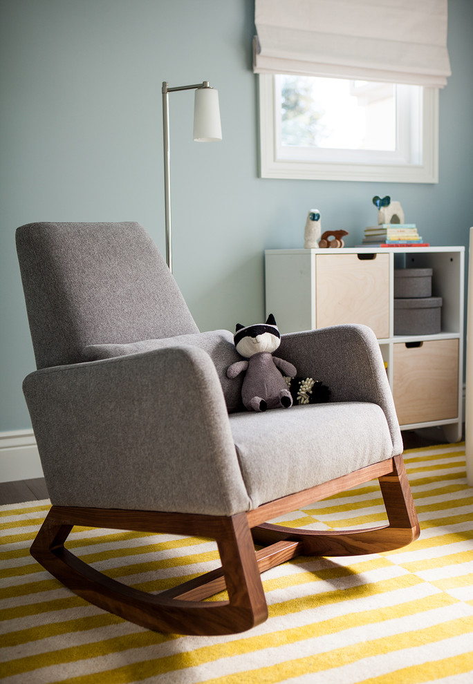 Imagen de habitación de bebé neutra moderna de tamaño medio con paredes azules y suelo de madera en tonos medios