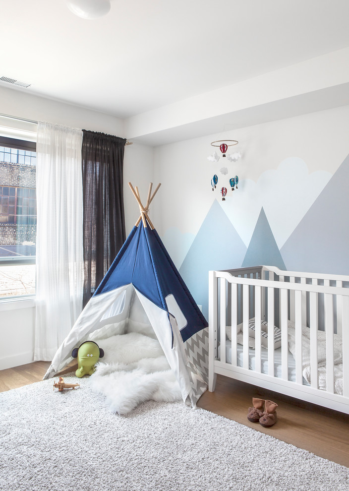 This is an example of a traditional gender neutral nursery in Toronto with multi-coloured walls, light hardwood flooring, beige floors and a feature wall.