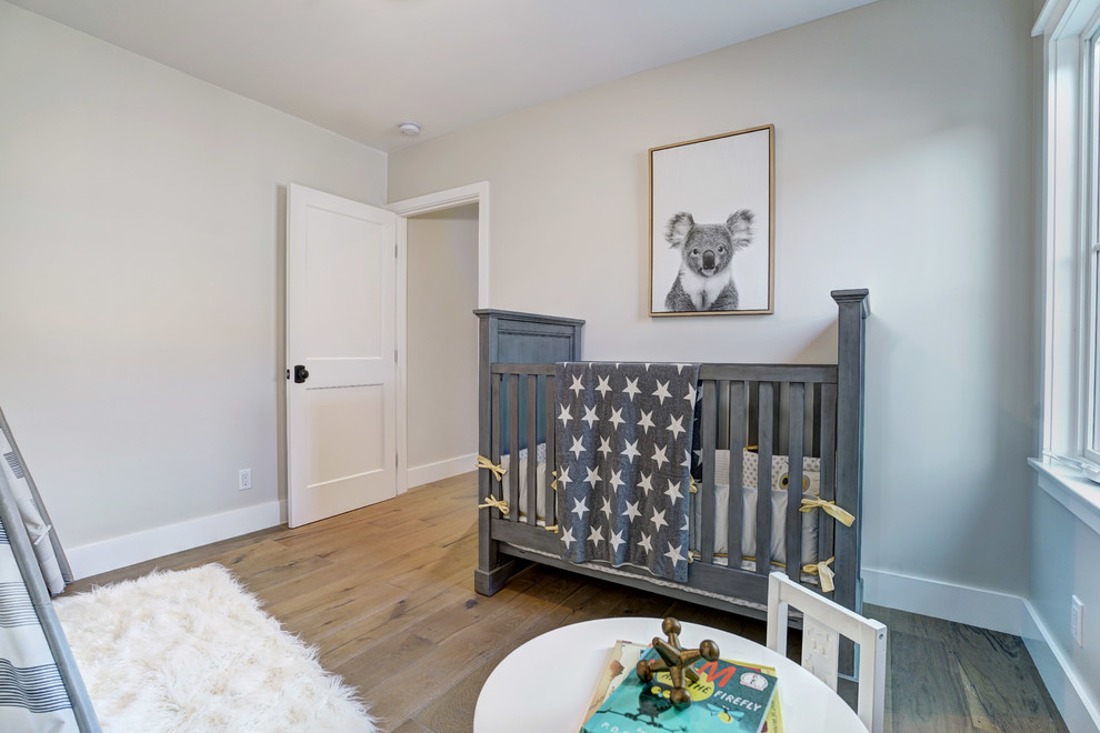 Modelo de habitación de bebé niño de estilo de casa de campo con paredes beige, suelo de madera en tonos medios y suelo marrón