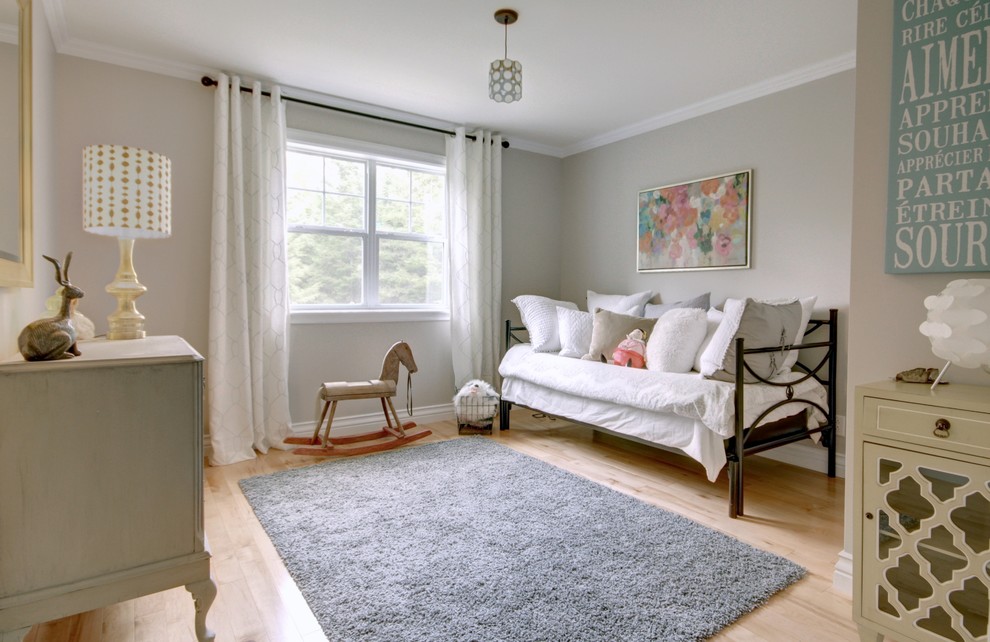 Diseño de habitación de bebé neutra clásica de tamaño medio con paredes grises, suelo de madera clara y suelo marrón