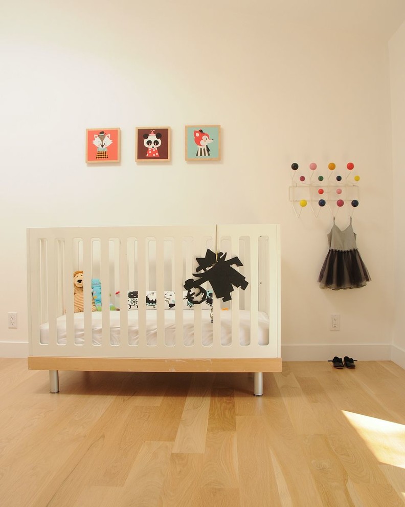 Imagen de habitación de bebé neutra nórdica con paredes blancas y suelo de madera clara