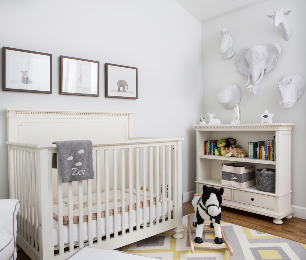 Cette image montre une chambre de bébé neutre traditionnelle avec un mur blanc et un sol en bois brun.