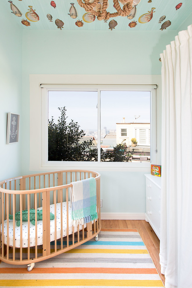 Immagine di una cameretta per neonati neutra chic di medie dimensioni con pareti blu e parquet chiaro