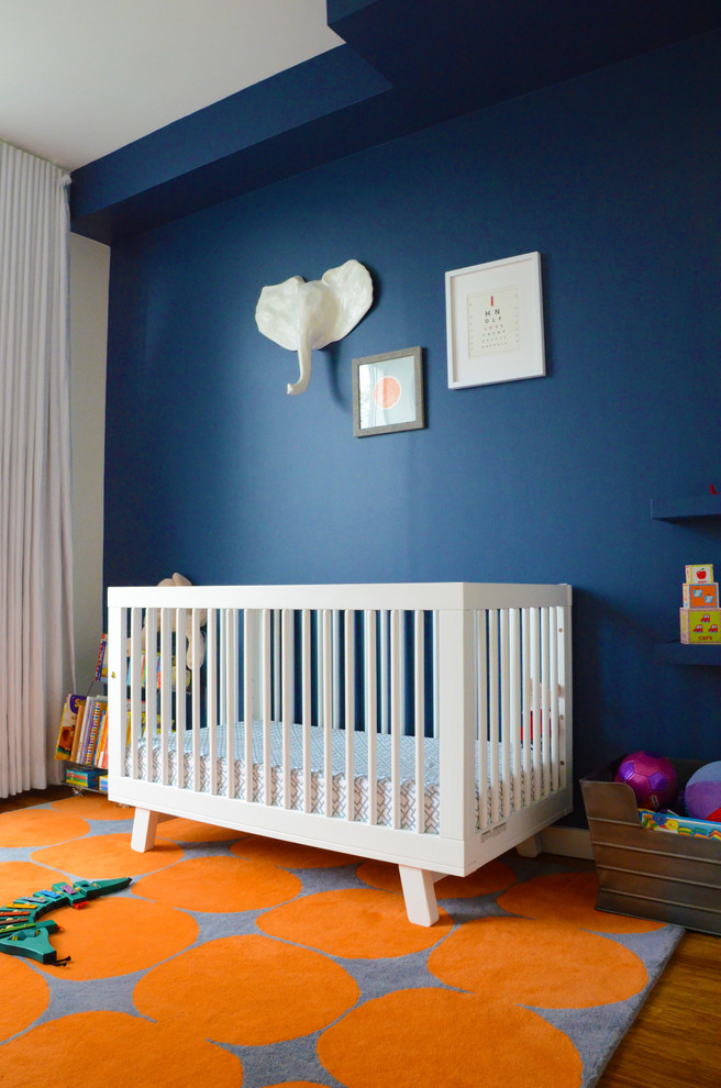 Bild på ett mellanstort eklektiskt babyrum, med blå väggar och mellanmörkt trägolv