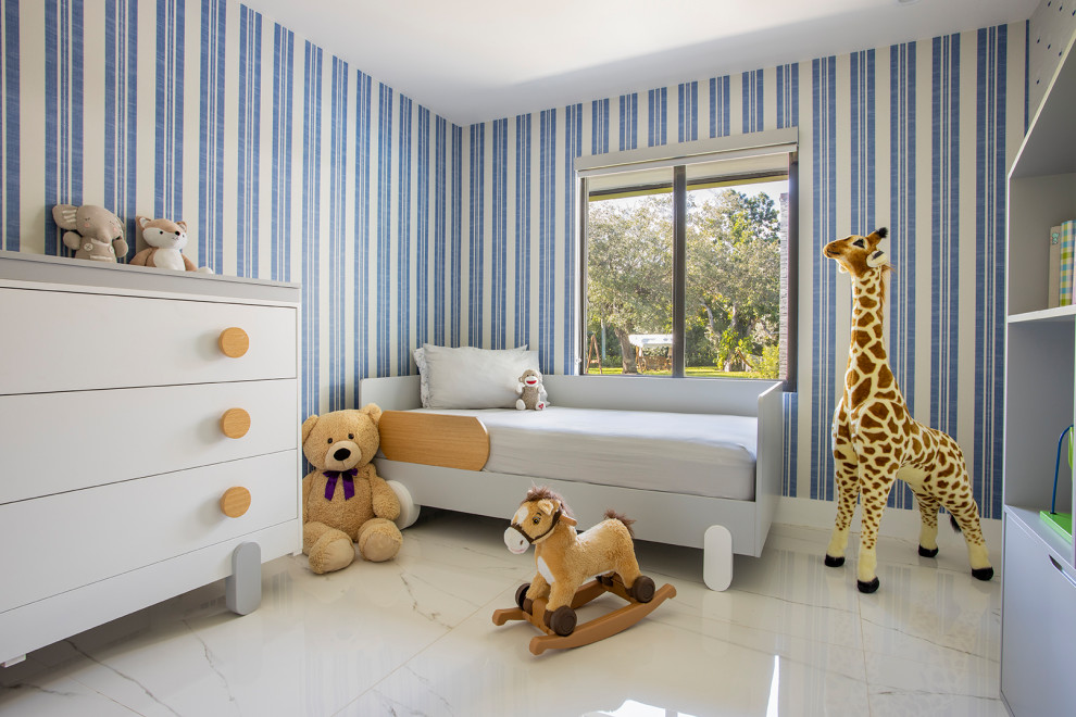 Idée de décoration pour une grande chambre de bébé garçon design avec un mur bleu, un sol en marbre et un sol blanc.
