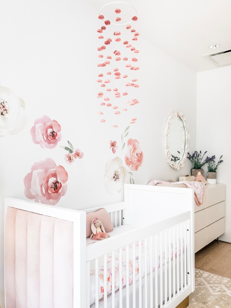 Cette photo montre une chambre de bébé fille chic de taille moyenne avec un mur blanc, parquet en bambou et un sol marron.