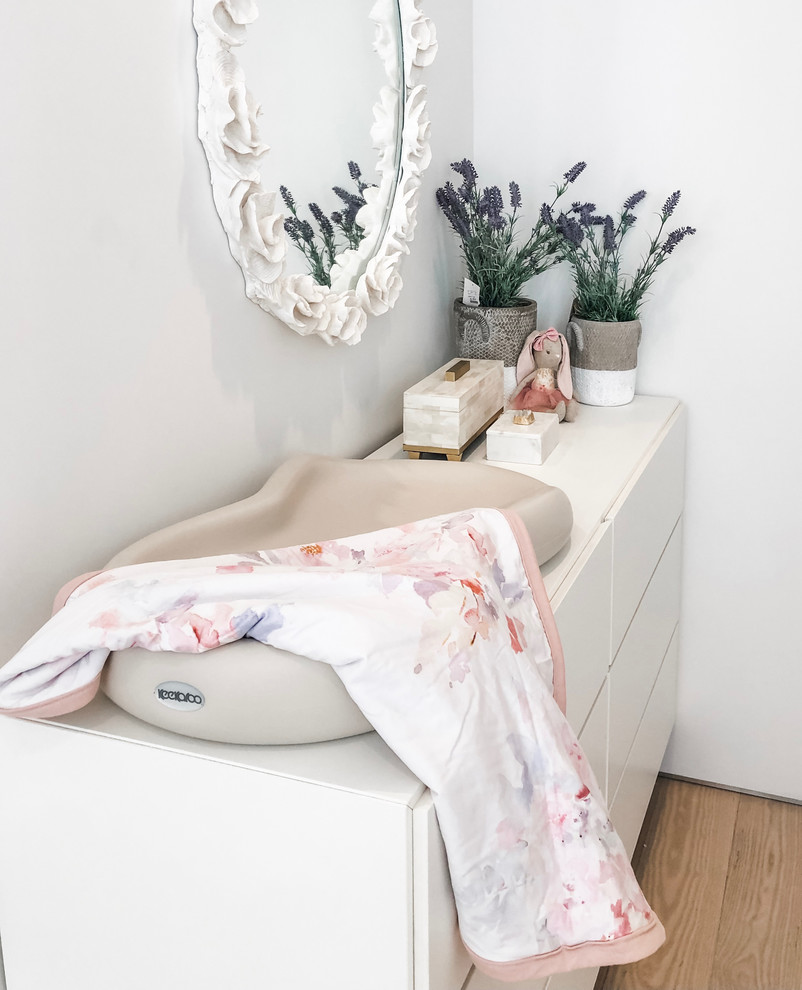 Idée de décoration pour une chambre de bébé fille tradition de taille moyenne avec un mur blanc, parquet en bambou et un sol marron.