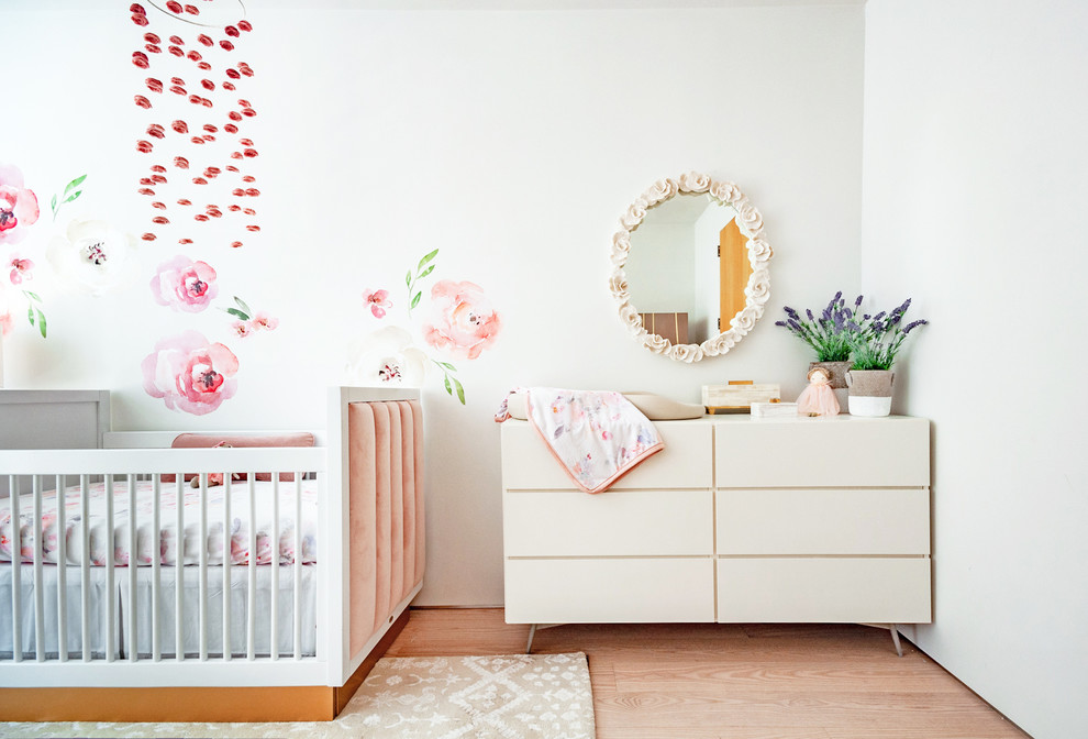 This is an example of a medium sized traditional nursery for girls in New York with white walls, bamboo flooring and brown floors.