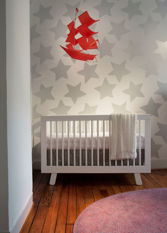 Ejemplo de habitación de bebé niño minimalista de tamaño medio con paredes blancas y suelo de madera en tonos medios