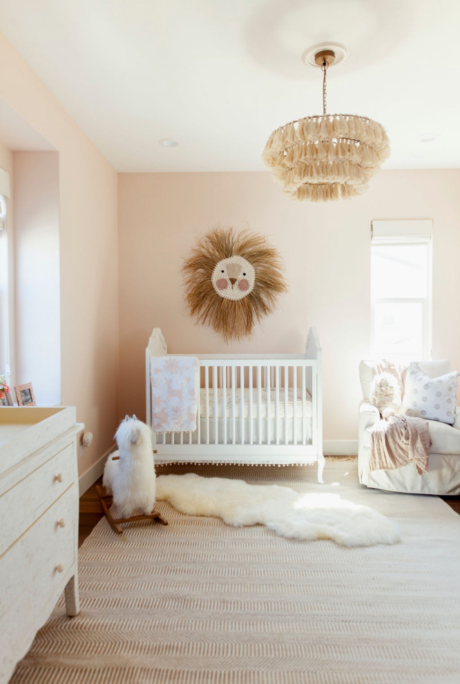 Diseño de habitación de bebé niña tradicional renovada con paredes rosas, suelo de madera oscura y suelo marrón