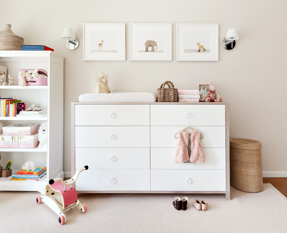 This is an example of a medium sized traditional nursery for girls in New York with beige walls and medium hardwood flooring.