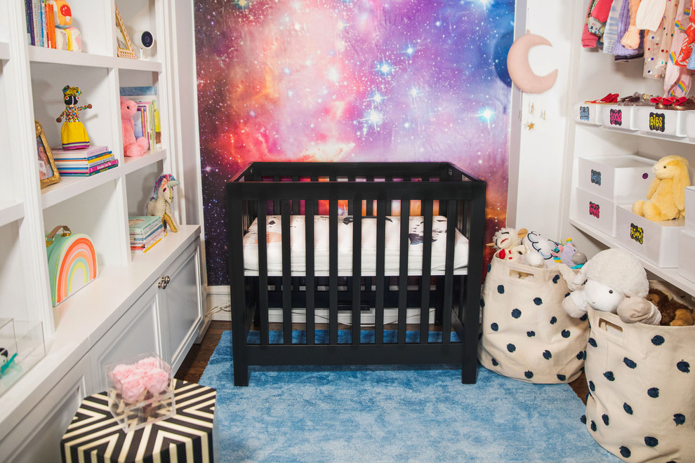 Photo of a small modern nursery for girls in New York with white walls, dark hardwood flooring and brown floors.