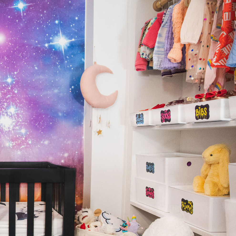 Photo of a small modern nursery for girls in New York with white walls, dark hardwood flooring and brown floors.