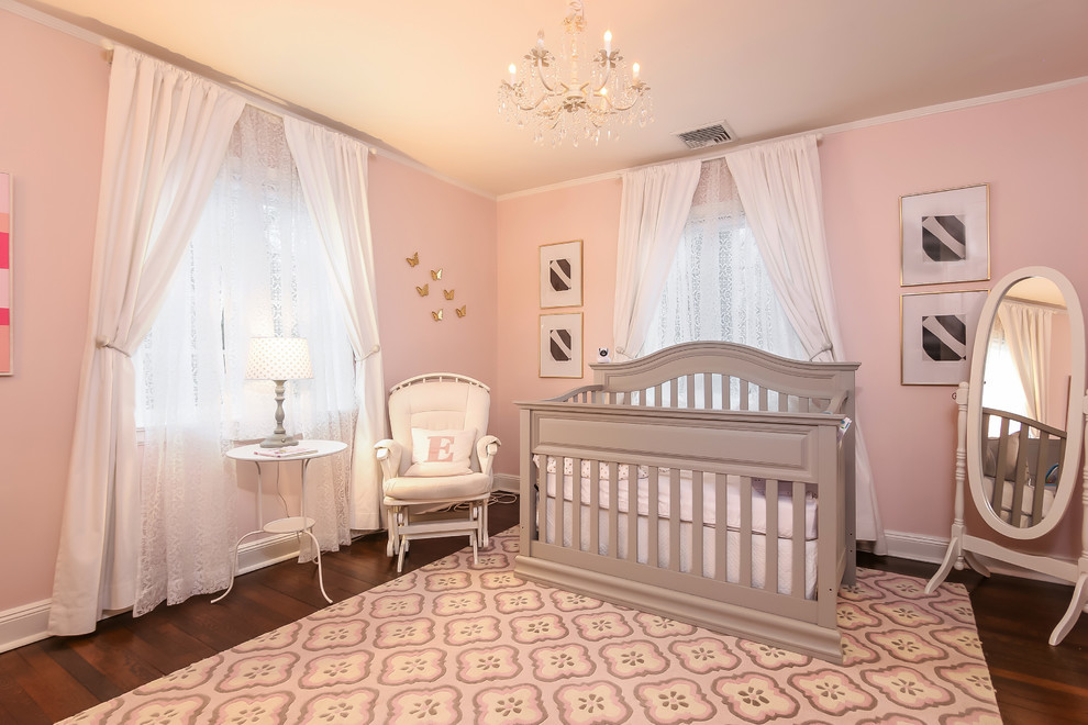 Immagine di una cameretta per neonata classica di medie dimensioni con pareti rosa