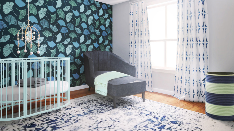 Modelo de habitación de bebé neutra contemporánea pequeña con paredes azules, suelo de madera en tonos medios y papel pintado