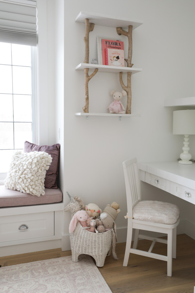Ejemplo de habitación de bebé niña clásica pequeña con paredes blancas y suelo de madera en tonos medios