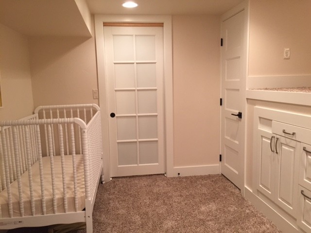 Modelo de habitación de bebé neutra tradicional pequeña con paredes blancas y moqueta