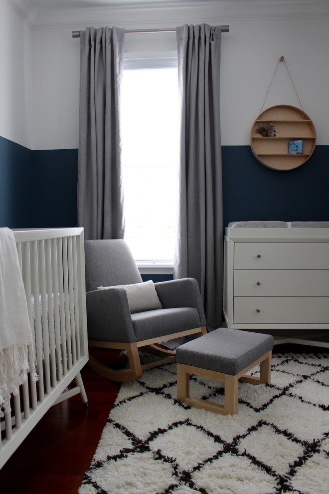 Exemple d'une chambre de bébé garçon moderne de taille moyenne avec un mur bleu et un sol en bois brun.