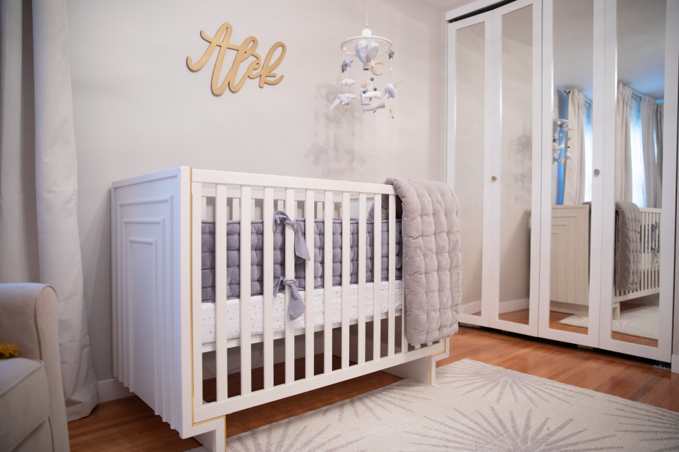 На фото: нейтральная комната для малыша среднего размера в стиле модернизм с серыми стенами, полом из ламината и коричневым полом с