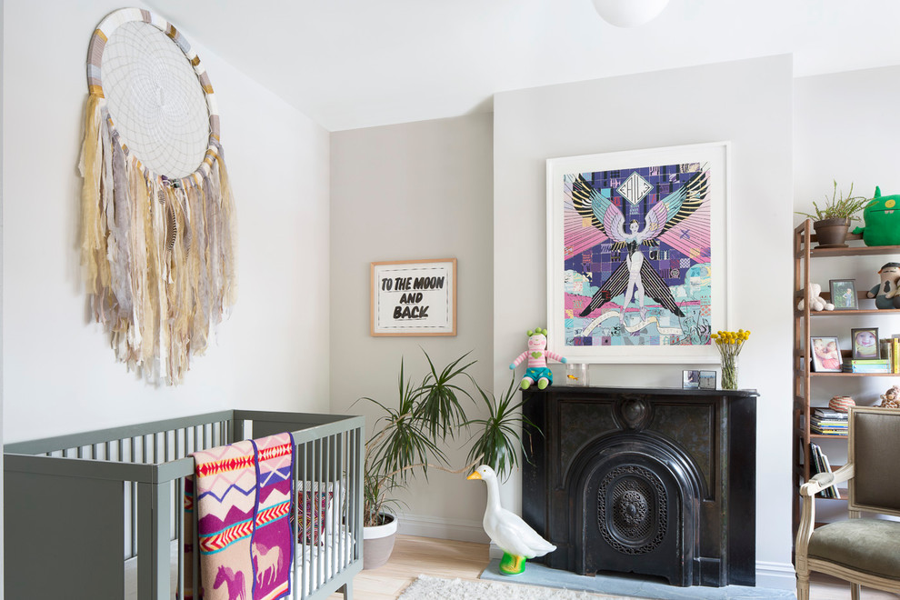 This is an example of a medium sized bohemian nursery for girls in New York with grey walls, light hardwood flooring, beige floors and a chimney breast.