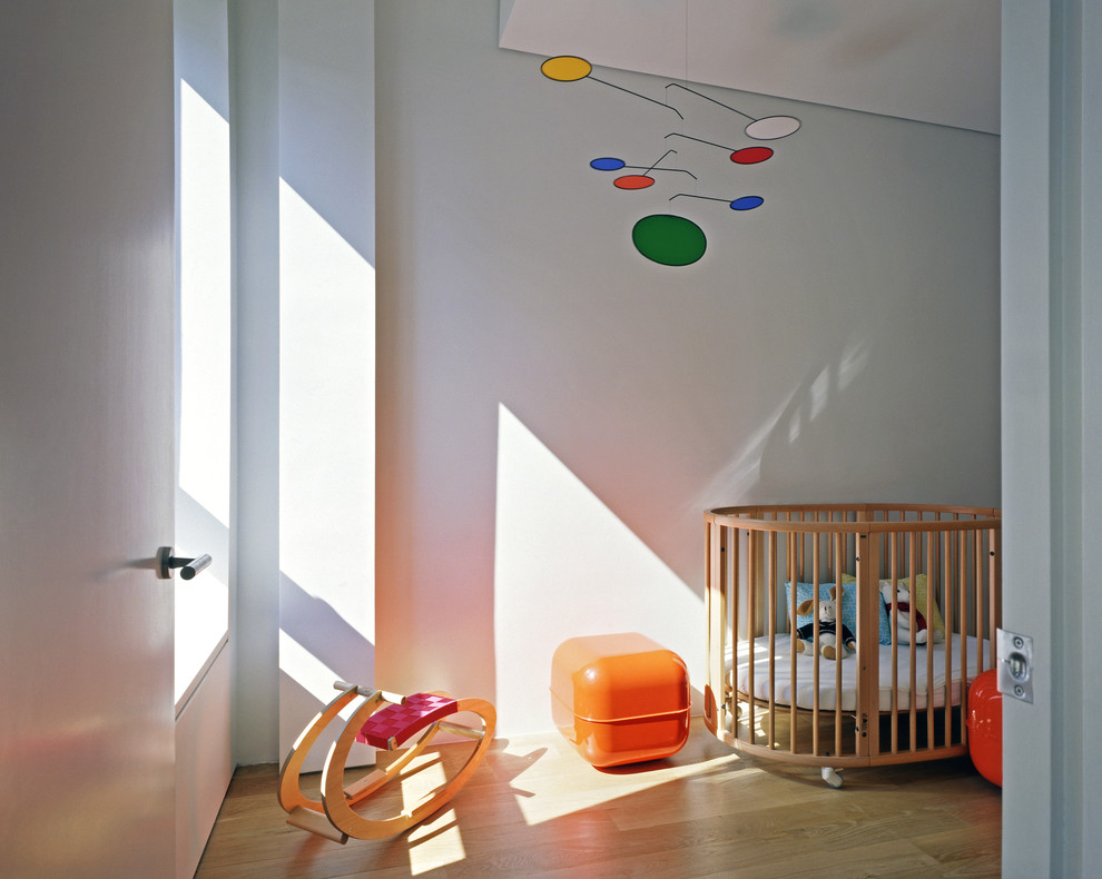 Neutrales Modernes Babyzimmer mit grauer Wandfarbe und hellem Holzboden in New York