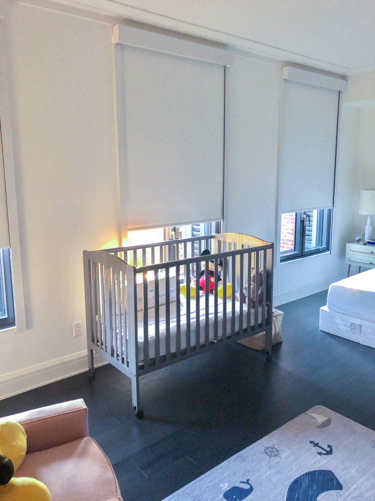 Foto de habitación de bebé neutra grande con paredes blancas, suelo de madera oscura y suelo negro