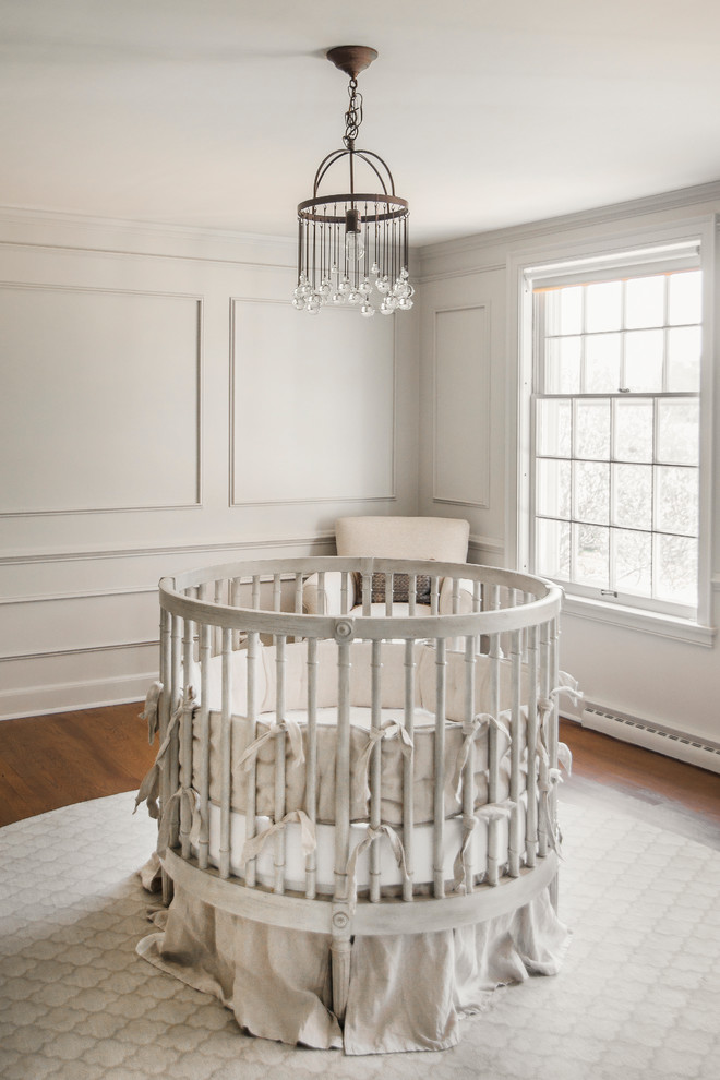 Foto de habitación de bebé neutra actual de tamaño medio con paredes grises y suelo de madera oscura