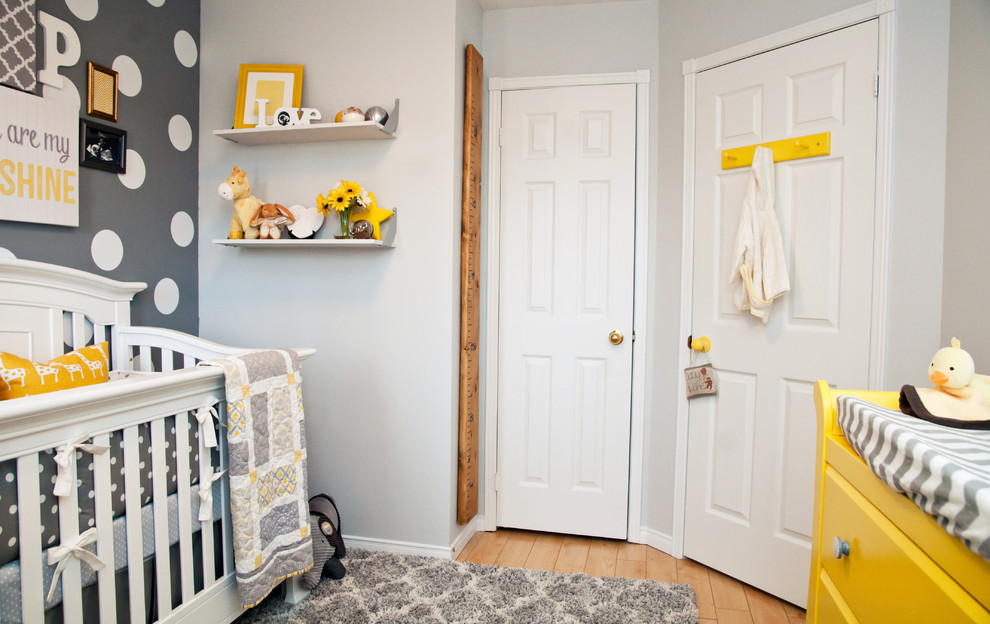 Diseño de habitación de bebé neutra tradicional renovada con paredes grises y suelo de madera en tonos medios