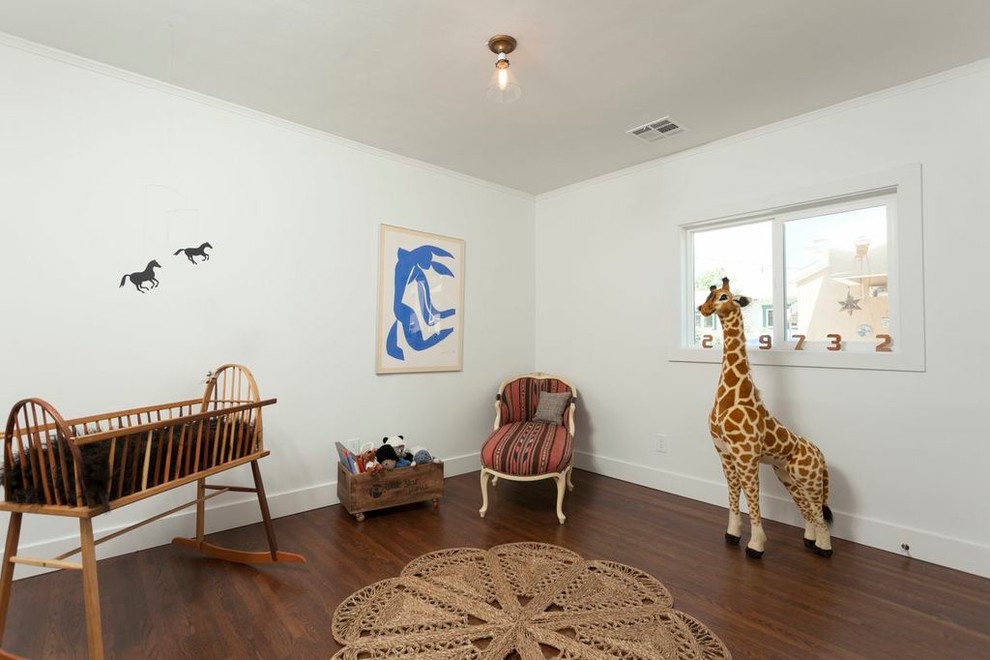 Imagen de habitación de bebé neutra ecléctica con paredes blancas, suelo de madera oscura y suelo marrón
