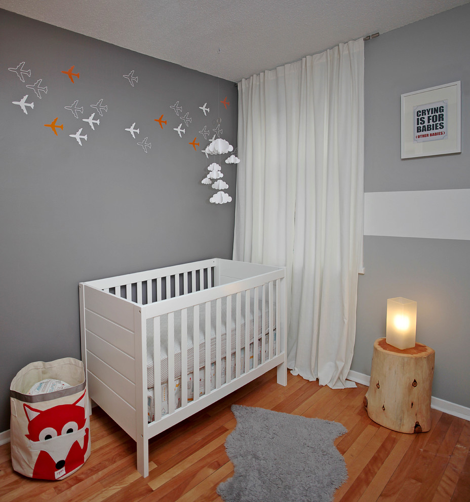 オタワにあるコンテンポラリースタイルのおしゃれな赤ちゃん部屋 (グレーの壁、男女兼用、無垢フローリング、オレンジの床) の写真