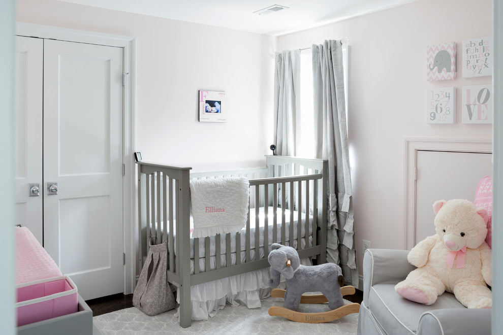 Ejemplo de habitación de bebé niña tradicional renovada de tamaño medio con paredes rosas y suelo de madera oscura