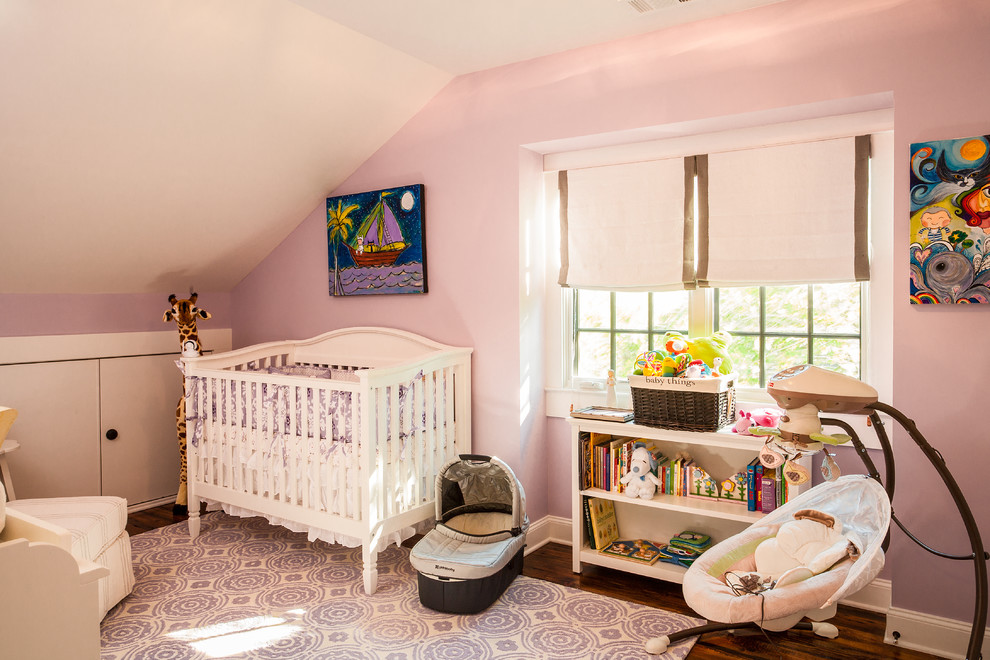 Diseño de habitación de bebé niña de estilo americano con paredes púrpuras y suelo de madera en tonos medios