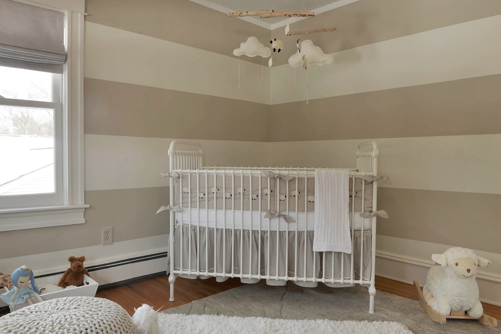 Immagine di una piccola cameretta per neonati neutra tradizionale con pareti bianche e pavimento in legno massello medio