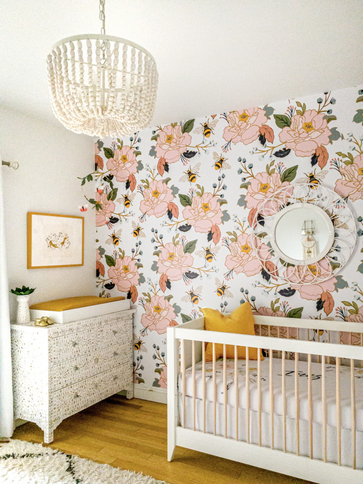 Modelo de habitación de bebé niña ecléctica de tamaño medio con paredes multicolor, suelo de madera clara y suelo marrón