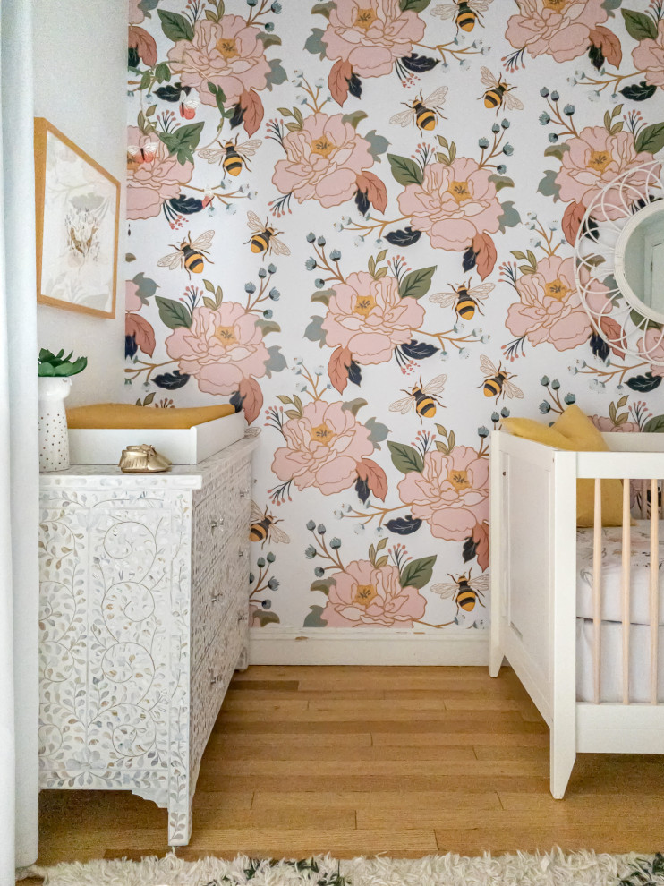 Medium sized bohemian nursery for girls in New York with multi-coloured walls, light hardwood flooring and brown floors.