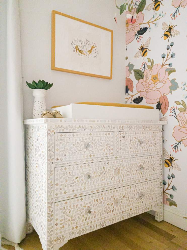 Immagine di una cameretta per neonata eclettica di medie dimensioni con pareti multicolore, parquet chiaro e pavimento marrone