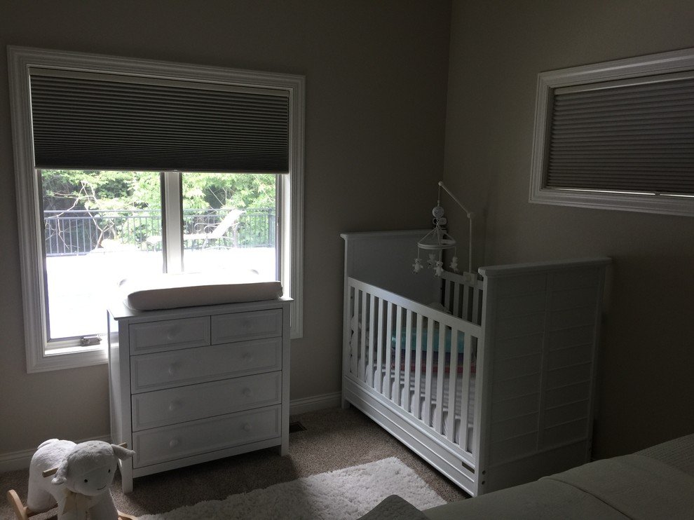 Modelo de habitación de bebé niña tradicional renovada de tamaño medio con paredes beige, moqueta y suelo beige