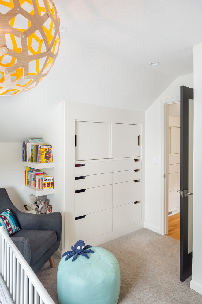 Foto på ett litet minimalistiskt babyrum, med vita väggar och heltäckningsmatta