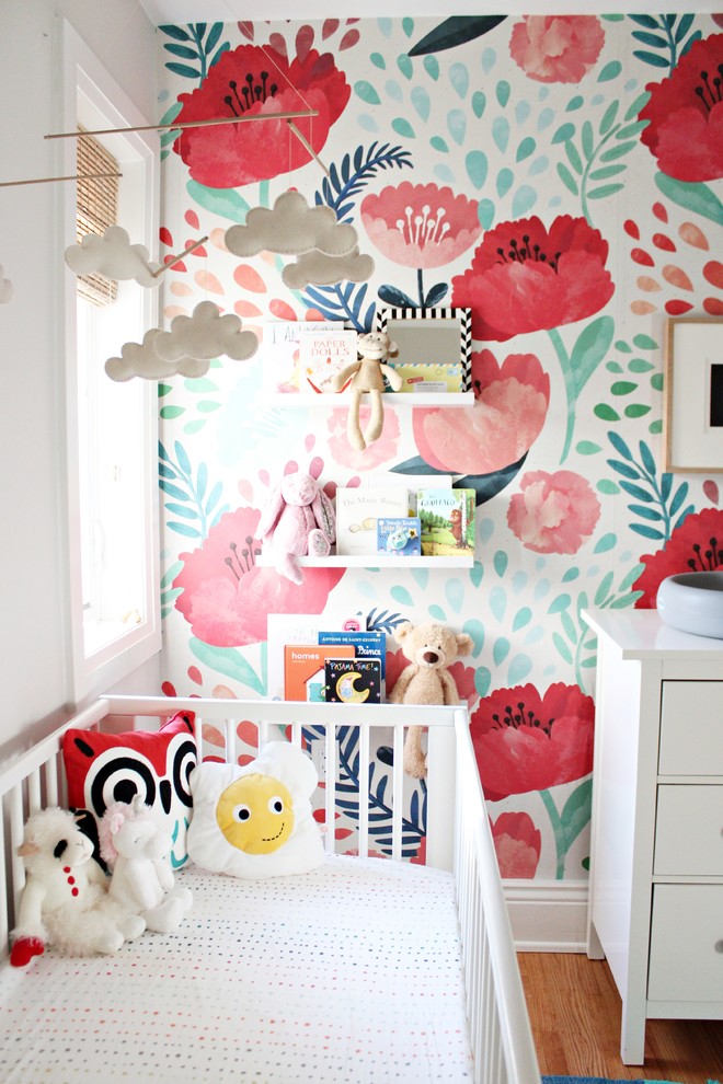 Ejemplo de habitación de bebé niña moderna de tamaño medio con paredes grises y suelo de madera clara