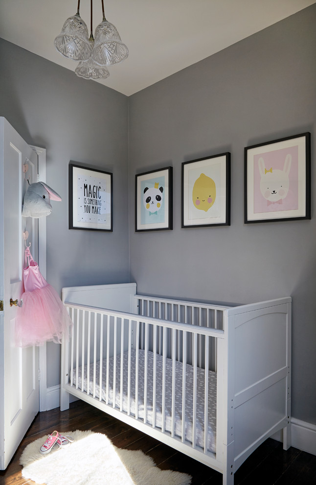 Diseño de habitación de bebé niña nórdica pequeña con paredes grises y suelo de madera oscura