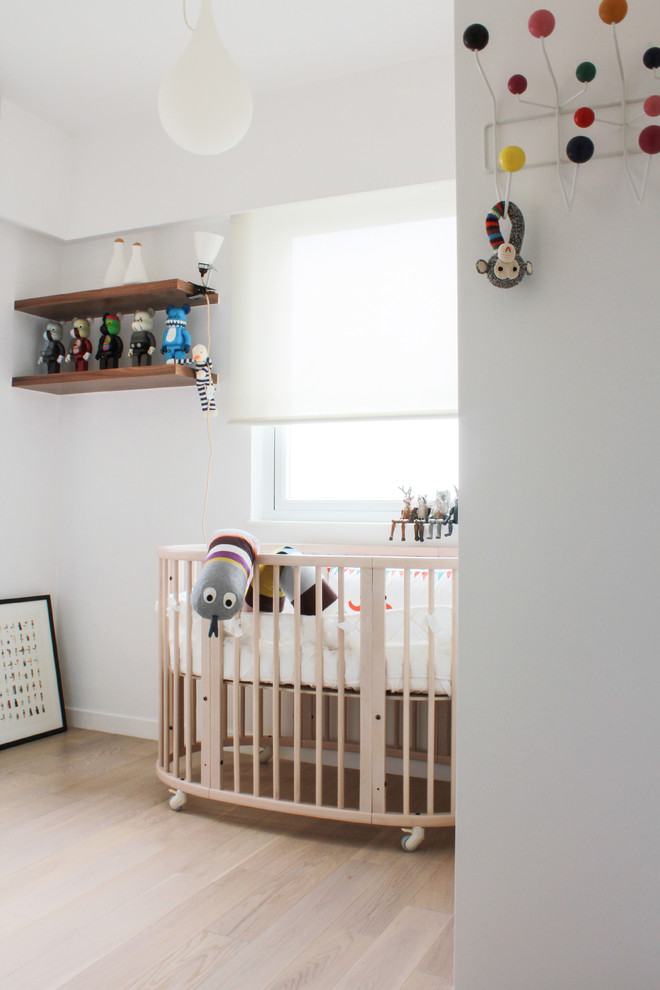 Cette image montre une chambre de bébé neutre minimaliste avec un mur blanc, parquet clair et un sol beige.