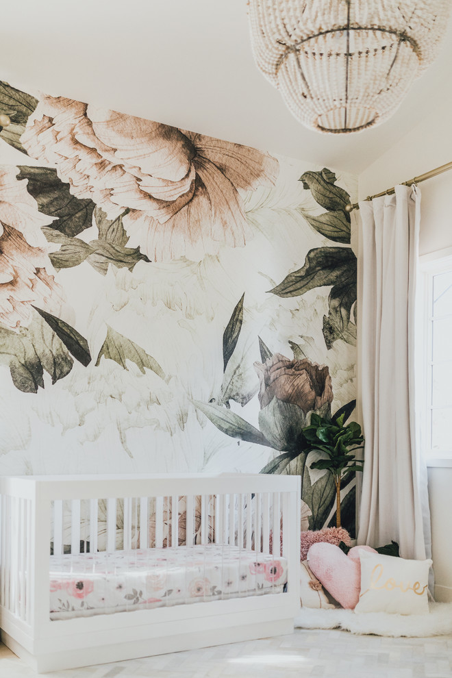 This is an example of a small traditional nursery for girls in Los Angeles with multi-coloured walls and light hardwood flooring.