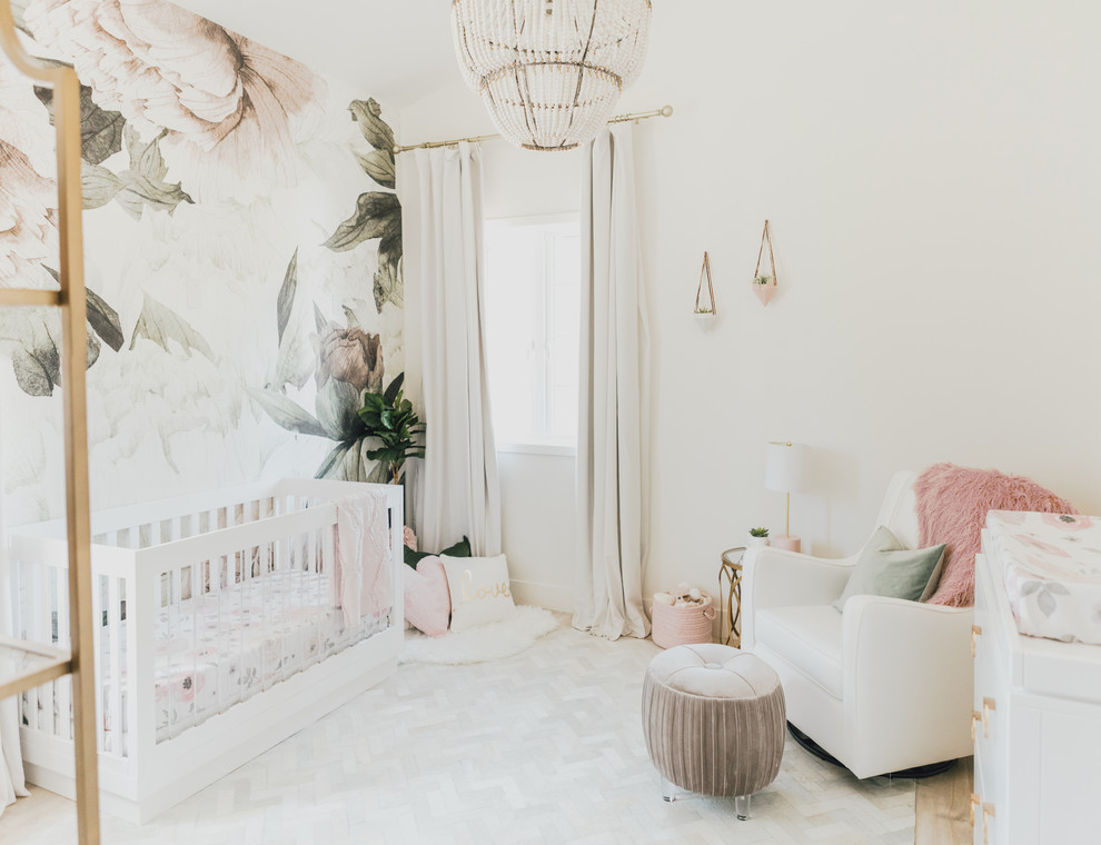 Small traditional nursery for girls in Los Angeles with multi-coloured walls and light hardwood flooring.