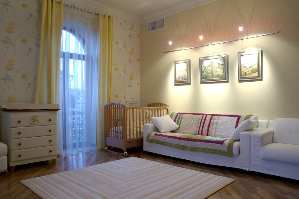 Esempio di una cameretta per neonata design con pareti gialle e pavimento in legno massello medio