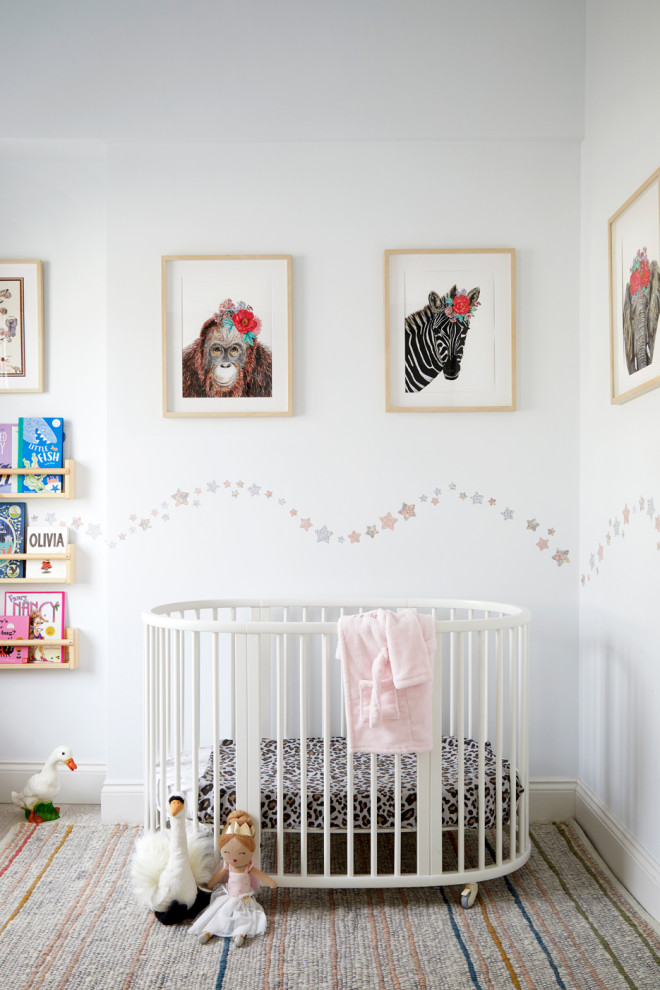 Immagine di una cameretta per neonata classica di medie dimensioni con pareti bianche