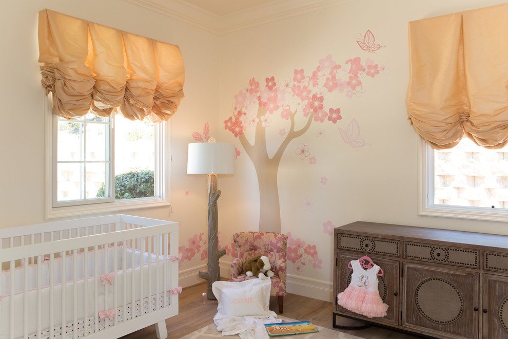 Modelo de habitación de bebé niña tradicional grande con paredes blancas y suelo de madera en tonos medios