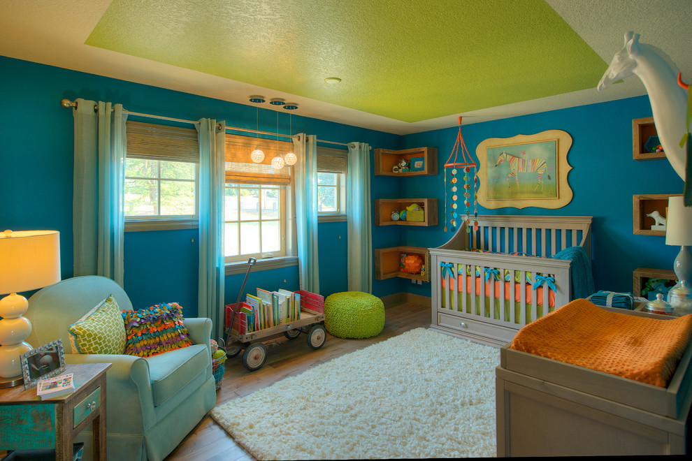 Large eclectic gender neutral nursery in Portland with blue walls, medium hardwood flooring and brown floors.